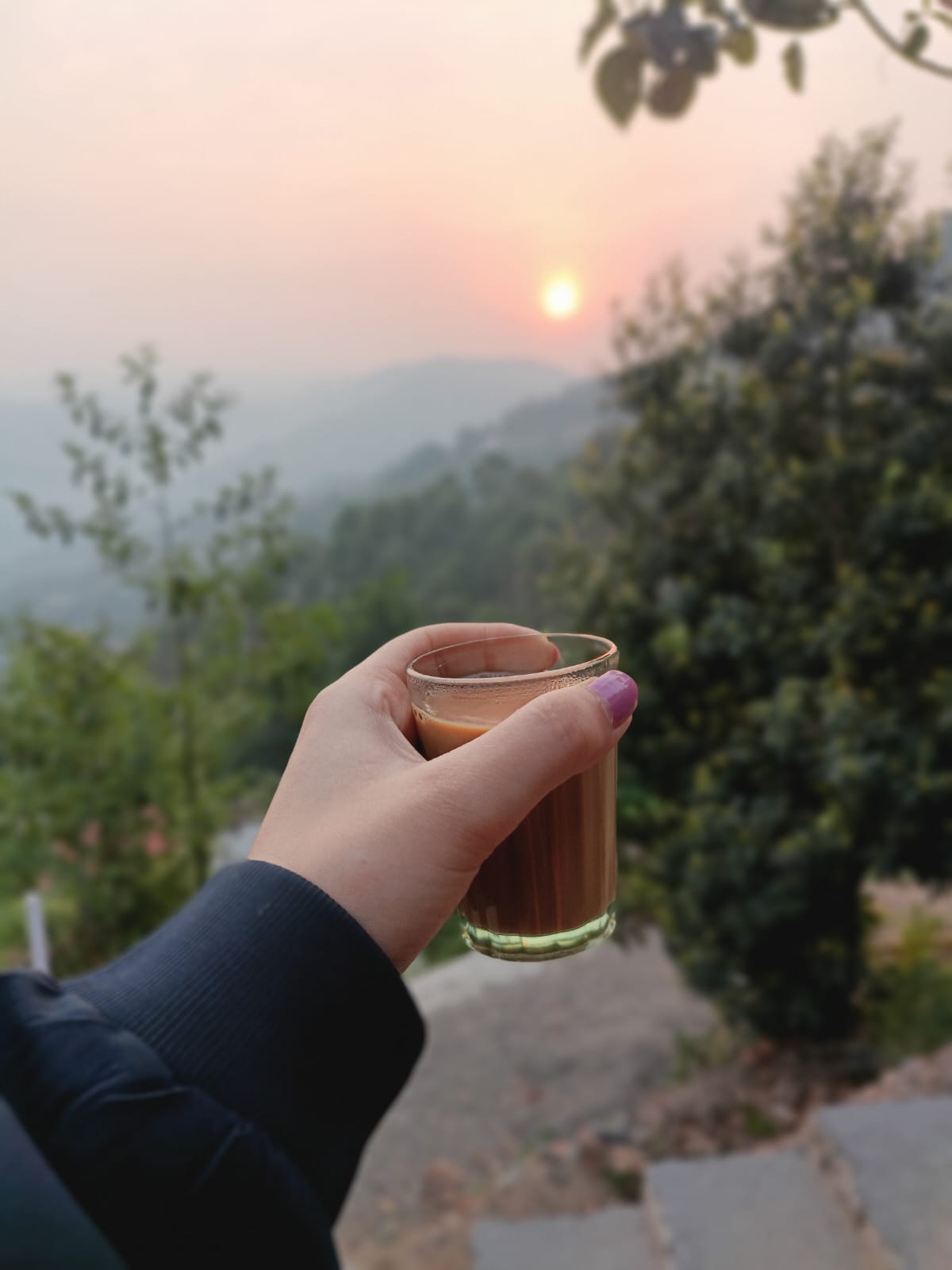 Hot pahadi chai with a scenic mountain view in the background