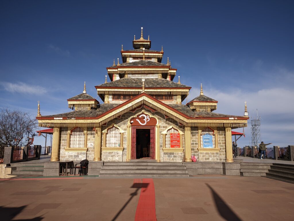 Kedarnath-style wooden temple with golden decorations under a clear blue sky in Uttarakhand